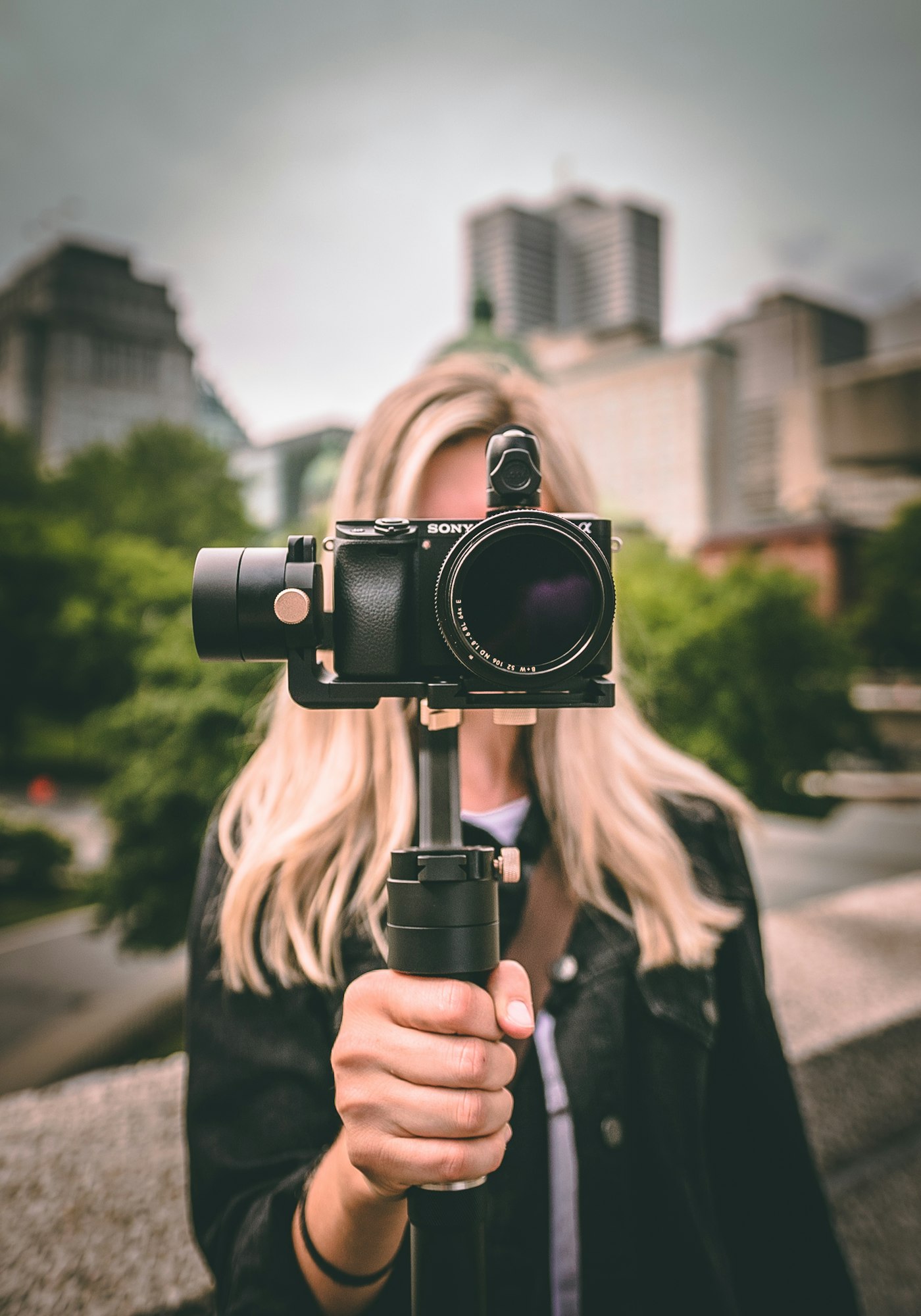 A camera balanced on a handheld gimbal, framed up on a street in the late afternoon