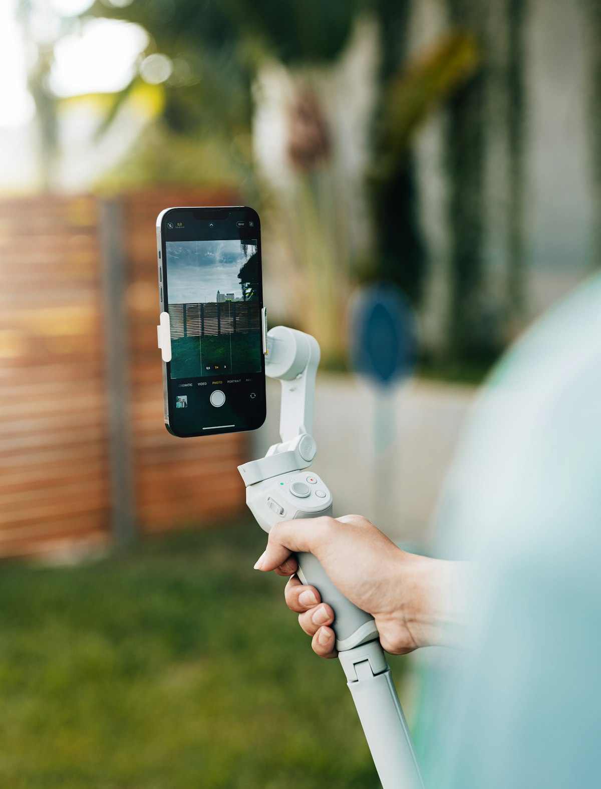 A phone mounted on a stabiliser, framed vertically, mid-shot in a garden